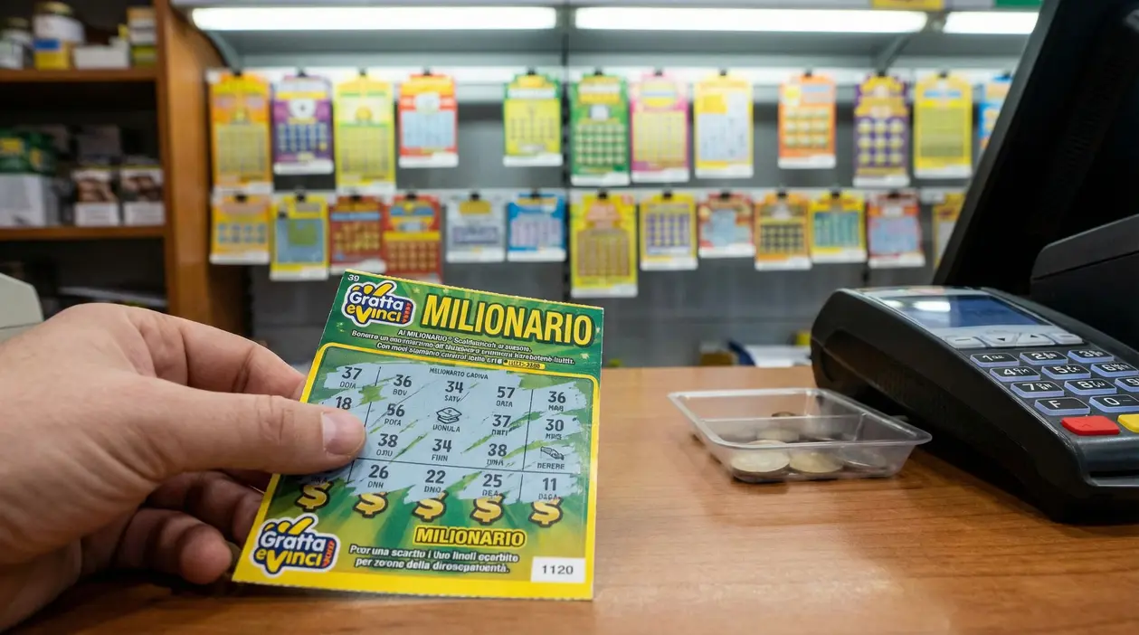Mano che tiene un Gratta e Vinci su un bancone di tabaccheria con schedine sullo sfondo